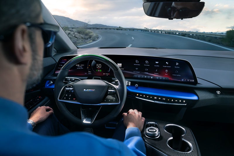 Front View of the 2026 OPTIQ-V Driving Through the Dusk Utilizing its Headlights | Deacon Jones Cadillac in Smithfield NC