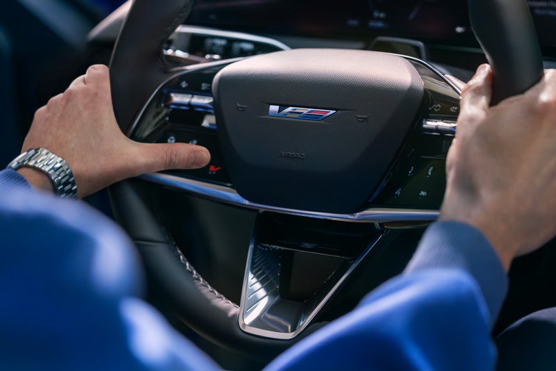 Close-up of a Man About to Press the V-Button on the 2026 OPTIQ-V Steering Wheel | Deacon Jones Cadillac in Smithfield NC